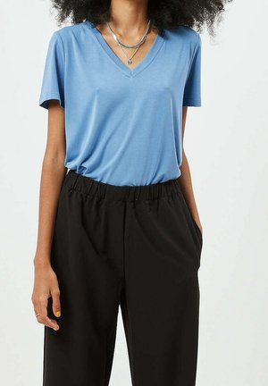 Hellblaues V-Ausschnitt-T-Shirt aus weichem Stoff, kombiniert mit locker sitzenden schwarzen Hosen mit elastischem Bund. Schlichtes Design mit kurzen Ärmeln.