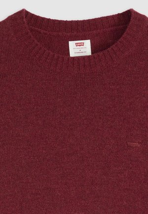 Suéter burdeos de cuello redondo hecho de un suave tejido de punto, con un cuello acanalado y un pequeño logotipo en relieve en el pecho. Ajuste estándar.