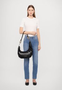 Saco hobo de couro preto com uma forma estruturada, alça curta e detalhes em tom de ouro. Textura suave com um emblema da marca na frente.