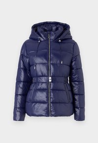 Marineblå dunjakke med en shiny finish, hette, glidelås og belte i midjen. Har kviltede paneler og sidelommer.
