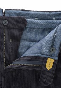Dunkelbraune Cordjacke mit einem Innenfutter aus blauem Fischgrätmuster, kontrastierendem Reißverschluss und glatter Textur. Mit einem Knopfakzent.