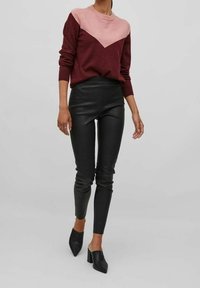 Burgundy- och rosa färgblockerad tröja med en chevrondesign, ihopparad med svarta höga läderleggings och svarta mules.