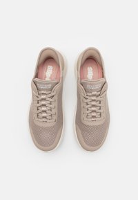 Tenisi bej din plasă, cu sistem de șireturi, suprafață texturată, branțuri roz pal și tălpi din cauciuc alb. Prezintă brandingul "Skechers Go Walk".