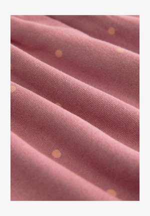 Lyserødt stof med subtil tekstur, der har hævede, runde, lyse orange polka dots. Materialet ser blødt og let strækbart ud.