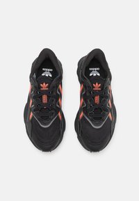 Mustat urheilukengät oransseilla yksityiskohdilla. Varustettu verkkokangasta ja synteettisiä materiaaleja, nauhakiinnitys ja pehmustettu varsi mukavuutta varten.