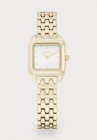 Montre bracelet rectangulaire en or avec un cadran blanc, présentant des chiffres romains aux positions 12 et 6, et un bracelet en métal à maillons. Le logo de la marque est affiché.