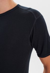 Sort kortærmet t-shirt lavet af blødt stof, med rund halsudskæring og diskrete syninger langs sømmene.