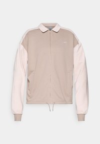 Nike ritsjack in beige met lichtroze mouwen, met een kraag, elastische manchetten en een trekkoord aan de onderkant. Geborduurd logo op de borst.