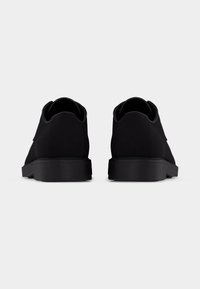 Μαύρα παπούτσια με απαλό, ματ φινίρισμα και χαμηλό προφίλ. Διαθέτουν παχιά ελαστική σόλα και διακριτικές λεπτομέρειες κατά μήκος των ραφών.