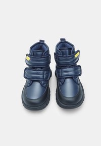 Granatowe buty wykonane z syntetycznej skóry z dwiema regulowanymi rzepami, wyściółką w kołnierzu i teksturowanymi czarnymi gumowymi podeszwami.