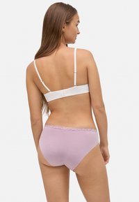 Ropa interior de color púrpura claro con un borde de encaje en la cintura. La tela parece suave y elástica, con un diseño de talle bajo.