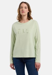 Világos zöld, hosszú ujjú póló kerek nyakkivágással, az elején fényes, kiemelt betűkkel "ELB" felirattal.