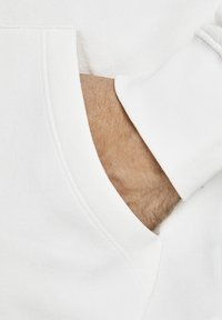 Witte sweatshirt met een buidelzak, voorzien van textuursleeves en geribbelde manchetten. De stof lijkt zacht en comfortabel.