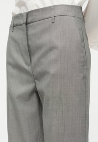 Γκρι, ραμμένο παντελόνι με απαλή υφή, επίπεδη μπροστινή όψη και πλαϊνές τσέπες. Διαθέτει κούμπωμα με κουμπί και φερμουάρ, με καθαρή, ίσια γραμμή.