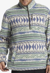 Fleece pullover med kvart lynlås, med et geometrisk mønster i blå, grøn og hvid. Tekstureret overflade og ribbede manchetter.