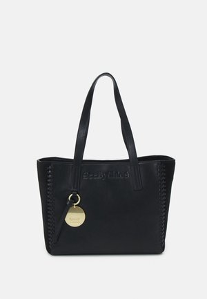 Black leather tote bag with braided side details, two shoulder straps, embossed logo, and a round gold logo charm hanging from one strap.