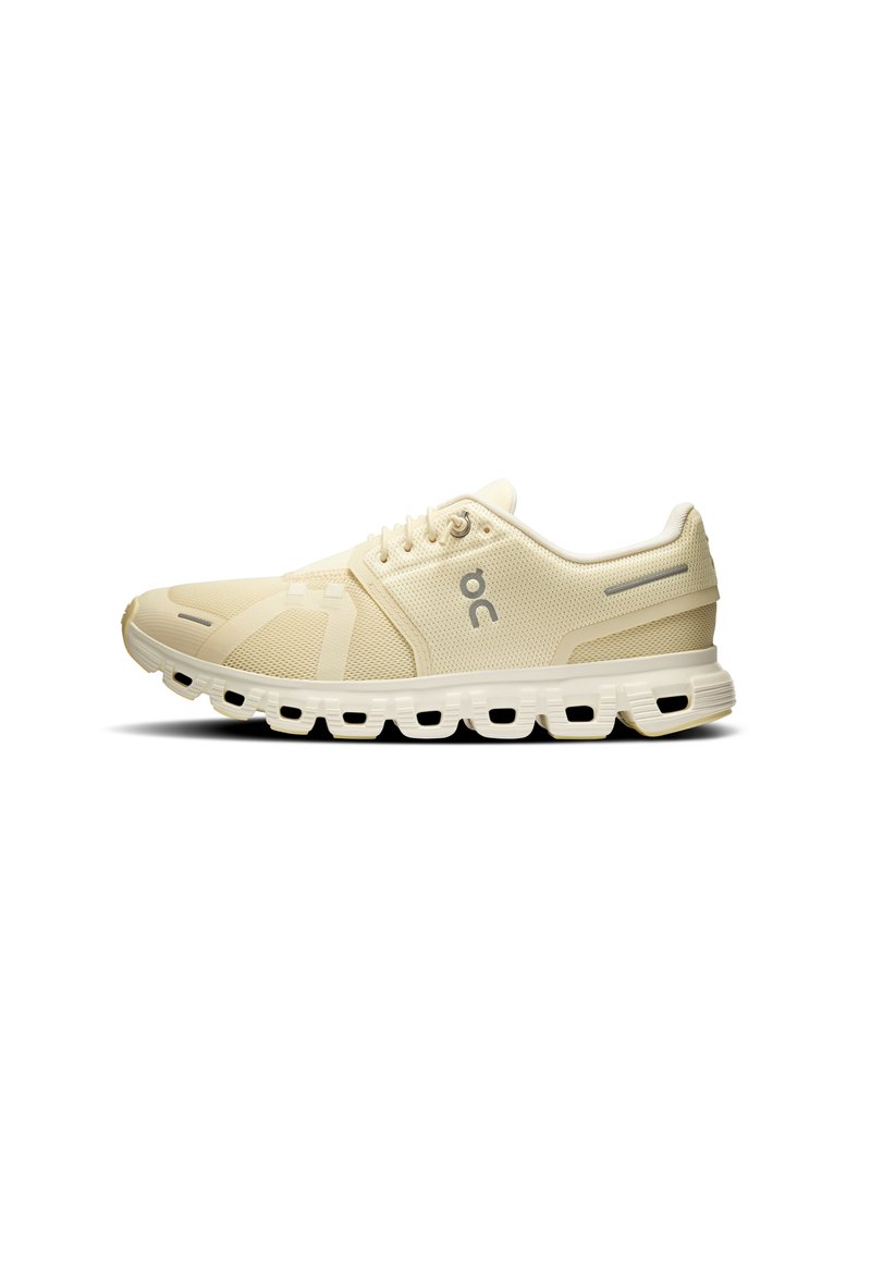 Zapatillas deportivas beige claro con parte superior de malla, detalles reforzados, suela acolchada y ranuras marcadas para flexibilidad y tracción.