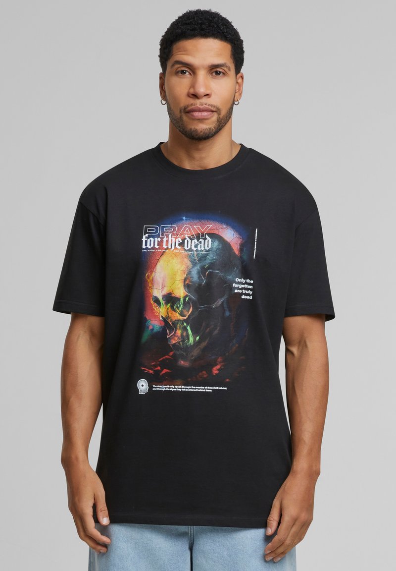 Sort t-shirt lavet af bomuld, med et farverigt kraniumgrafik og teksten "PRAY for the dead" samt en lyseblå accent. Korte ærmer og rund hals.