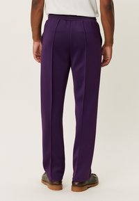 Pantalones morados a medida con parte delantera plana, cintura elástica y piernas rectas. El material parece liso con un ligero brillo.