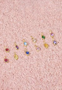 Orecchini in metallo dorato con gemme ovali dai colori multicolori in rosso, verde, blu, viola, rosa e giallo, posti su granuli di sale rosa.