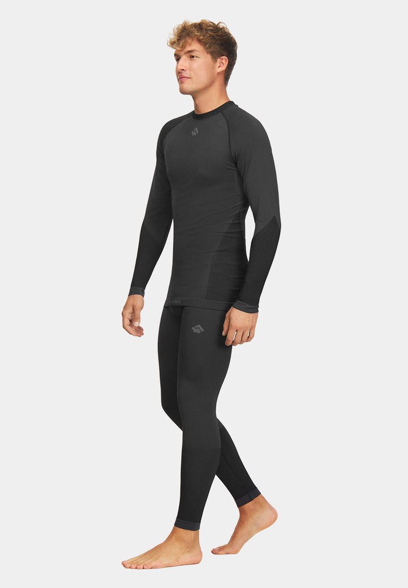 Czarny zestaw bazy sportowej z długim rękawem i dopasowanymi legginsami; obecne są teksturowane panele i akcenty z logo.