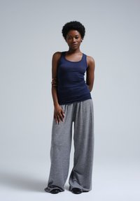 Canottiera blu navy e pantaloni da tuta grigi a gamba larga indossati da un modello, caratterizzati da una consistenza morbida e una vestibilità comoda, con una vita liscia.