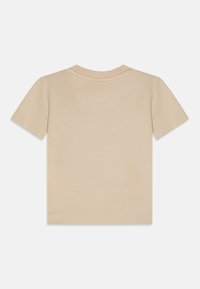 Beige lyhythihainen t-paita, jossa pyöreä pääntie ja pehmeä puuvillainen pinta. Siinä on siistit saumat ja tavallinen istuvuus.