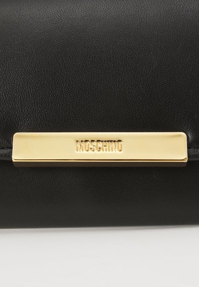 Clutch in pelle nera con una superficie testurizzata, caratterizzata da una placca in metallo dorato con la scritta "Moschino" in rilievo. Forma rettangolare elegante.
