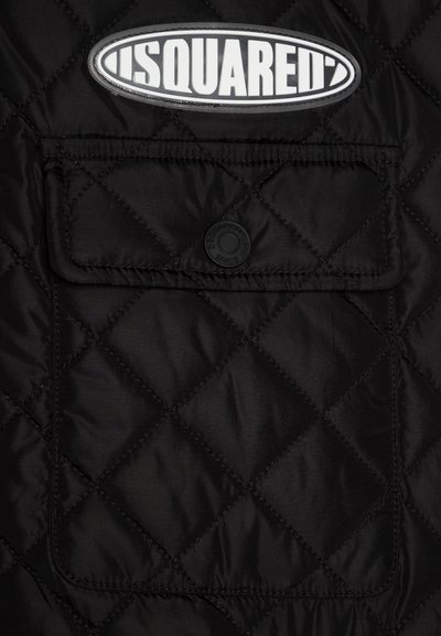 Gilet trapuntato nero con un evidente logo circolare bianco. Presenta una tasca frontale con chiusura a scatto e cuciture a rombi.