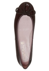 Ballerine plate en cuir lisse marron foncé avec un bout rond et un nœud torsadé sur le dessus, dévoilant une doublure intérieure rose pâle et le nom de la marque.