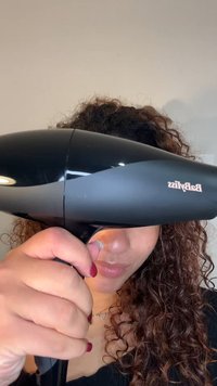 Fekete hajszárító elegáns kialakítással, az előre néző légbefúvó fúvókával. Ívelt test, fényes felület és látható "Babyliss" logó.