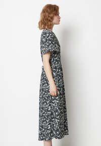 Abito stampato floreale in bianco e nero con maniche corte, vita alta e gonna fluida, che arriva a metà polpaccio, tessuto di texture liscia.