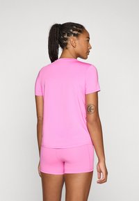 Rosa treningssett bestående av topp og shorts. Glatt, elastisk stoff med rund hals og korte ermer. Med logo og tettsittende design.