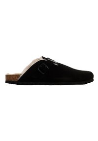 Zapatilla de ante negra tipo slip-on con un suave forro de piel sintética blanca, plantilla de corcho y una única correa ajustable con hebilla. Suela de goma texturizada.