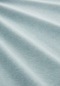 Lichtblauwe katoenen stof met een gladde textuur en een zichtbaar dicht geweven patroon, met subtiele kleurvariaties en een zachte val.
