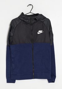Nike zip-hoodie med en svart övre del med texturmönster och en marinblå lägre del, tillverkad av mjukt tyg med justerbar huva.