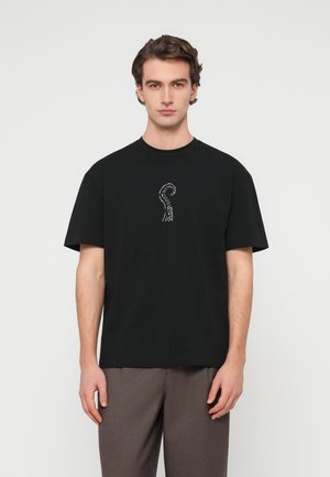 Schwarzes Baumwoll-T-Shirt mit kurzen Ärmeln, das ein weißes grafisches Design eines Oktopus-Tentakels zeigt. Der Stoff wirkt glatt und leicht.
