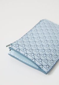 Portafoglio blu con un motivo geometrico di linee e cerchi intrecciati, realizzato in materiale testurizzato, dotato di chiusura a zip e interno a contrasto.