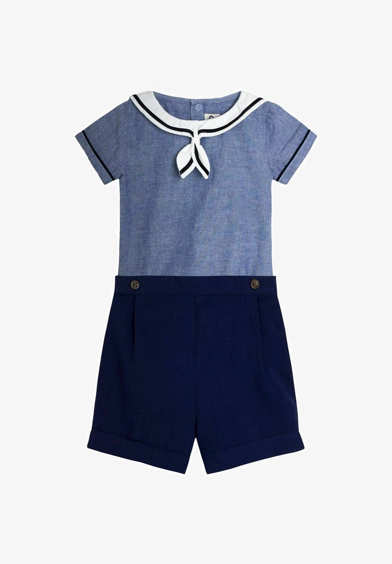 Tutina corta a maniche corte blu con colletto da marinaio bianco e pantaloncini blu navy con dettagli a bottoni e orli risvoltati.