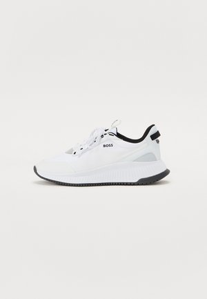 Weißer Sportschuh mit strukturiertem Stoff, schwarzen Akzenten und einer gepolsterten Sohle. Verfügt über eine Schnürung und ein Logodetail an der Seite und Ferse.
