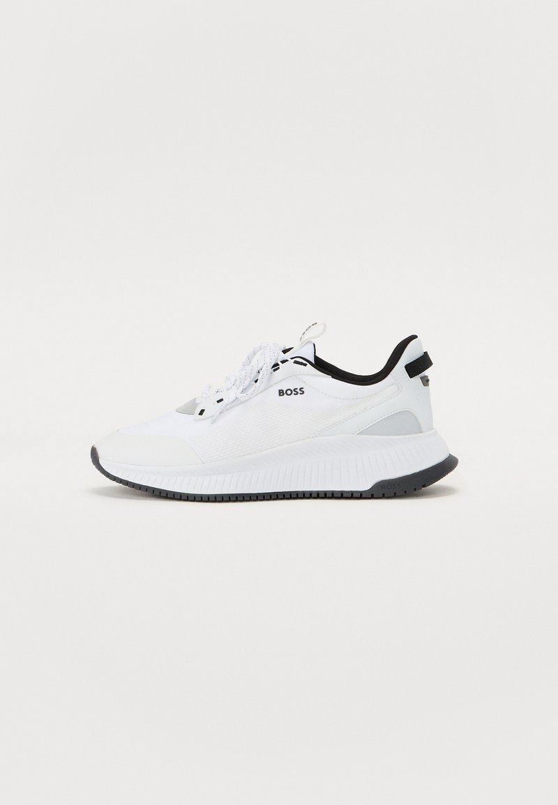 White athletic sneaker with textured fabric, black accents, and a cushioned sole. Features lace-up closure and logo detail on the side and heel.