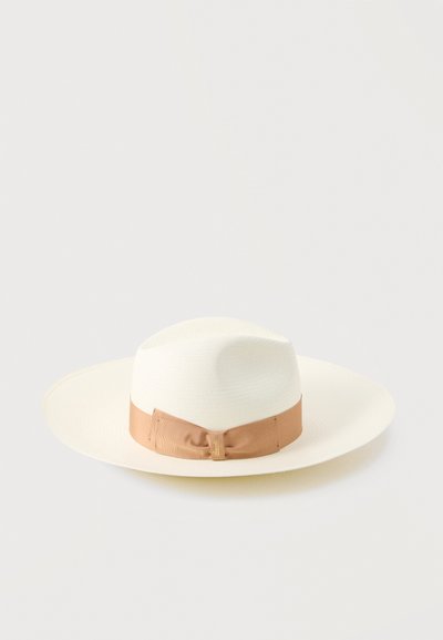 Λευκό καπέλο με ευρύ γείσο, με υφασμάτινη ταινία σε καφέ χρώμα και φιόγκο, απεικονίζεται σε απλό φωτεινό γκρι φόντο.