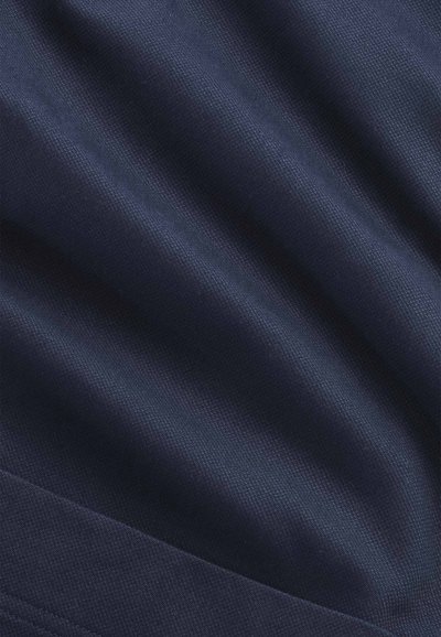 Tessuto blu navy con trama finemente strutturata e pieghe diagonali visibili che creano ombre morbide e punti luce.