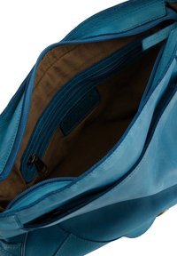 Blauwe leren handtas met een ritssluiting aan de bovenkant, voorzien van een bruine stoffen binnenvoering en een binnenvak met ritssluiting. Merkenlabel zichtbaar aan de binnenkant.
