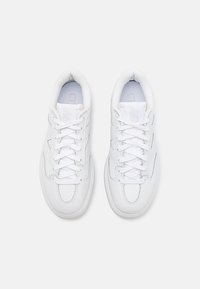 Paire de baskets blanches New Balance avec lacets, vues de dessus sur un fond blanc uni.