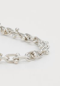 Pulsera de cadena de plata con eslabones redondeados y pequeños acentos esféricos en cada eslabón, sobre un fondo blanco.