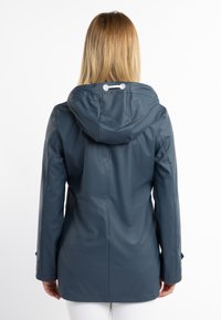 Impermeable abrigo de lluvia azul con capucha, mangas largas y dos bolsillos laterales. Textura suave con cordón ajustable en el cuello.