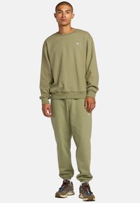 Olivgrüner Sweatshirt und passende Sweatpants aus weicher Baumwolle, mit gerippten Bündchen und einem kleinen Logo auf der Brust.