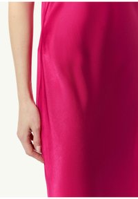 Fuksjowa satynowa sukienka o gładkiej fakturze, z lekkim połyskiem. Ręka trzyma bok, pokazując układ i sylwetkę.