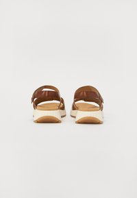Sandales en cuir brun avec des sangles réglables, un pied à coussin et des semelles texturées blanches. La vue arrière met en avant le design et la forme.